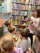 Pracownik biblioteki prezentuje dzieciom książki