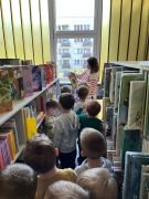 Pracownik biblioteki prezentuje dzieciom książki