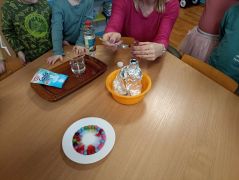 Nauczyciel prowadzący eksperyment przy stoliku z dziećmi.