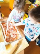 Dzieci posypują ser na pizzę