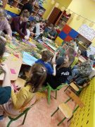 Dzieci z rodzicami tworzą palmy wielkanocne.