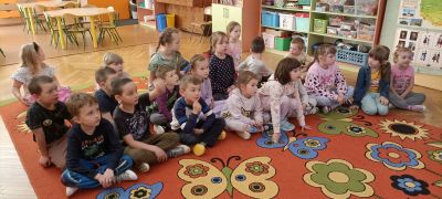 Dzieci czekają na zajęcia siedząc na dywanie.