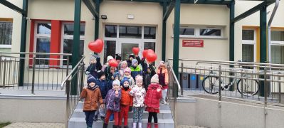 dzieci przed przedszkolem z balonami w sercami
