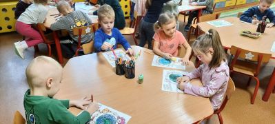 dzieci wykonują karty pracy przy stoliku