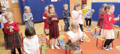dzieci tańczą choreografię z wykorzystaniem krzesełek i telefonów
