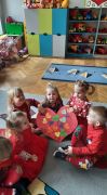dzieci siedzą na dywanie i trzymają laurkę z sercem