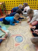 dzieci kolorują kredkami kosmiczną kolorowankę