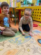 chłopcy siedzą na podłodze i kolorują planetę 