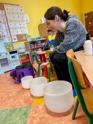 masażystka prezentuje kryształowe misy i wydawane z nich dźwięki