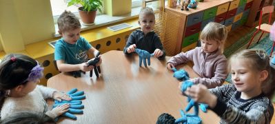 dzieci przy stolikach sprawdzają, co znajduje się w rękawicach