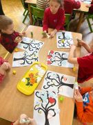 dzieci ozdabiają drzewo papierowymi sercami 