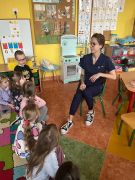 dentystka siedzi na krześle, a przed nią dzieci