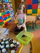 dziewczynka wsypuje ziemię do doniczki 