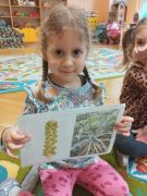 dziewczynka trzyma obrazek przedstawiający jak rośnie brukselka