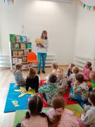 Pracownik biblioteki prezentuje dzieciom książkę 