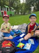 dwóch chłopców siedzi na kocyku z przekąskami