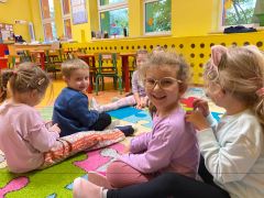 Dzieci siedzi na dywanie i wykonuje sobie nawzajem masażyki