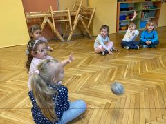 Dzieci siedzą w kręgu i rzucają sobie kłębek sznurka