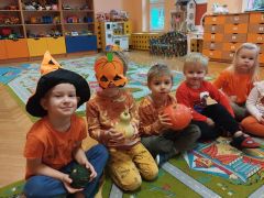 Dzieci siedzą na dywanie i trzymają dynie