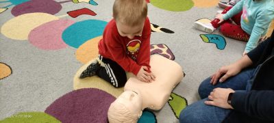 Dziecko uczy się masażu serca na fantomie.