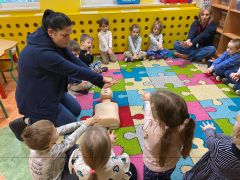 Pani ratownik pokazuje dzieciom  jak się wykonuje masaż serca