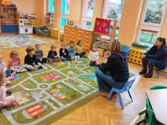 Dzieci siedzą na dywanie i słuchają Pani Ratownik