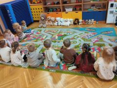 Dzieci i misie siedzą na dywanie.