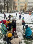 Dzieci lepią misia ze śniegu.