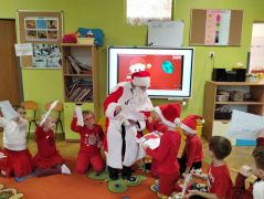 Dzieci wrzucają swoje listy do worka Mikołaja.