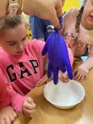 Dziewczynka ściska rękawiczkę z której wypływa mleko.