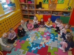 Dzieci siedzą w kole na dywanie.